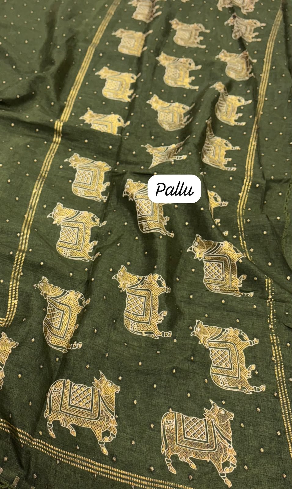 Olive green saree fabric featuring intricate gold-toned cow motifs and a labeled Pallu section.