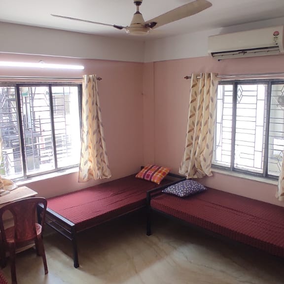 Shared bedroom featuring two twin beds with maroon covers and an air conditioner