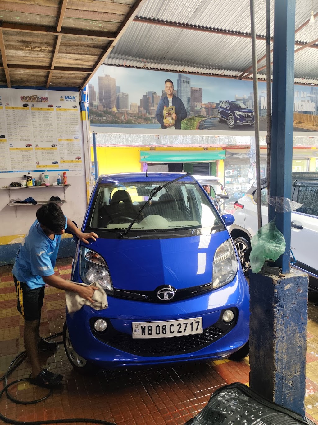 A mechanic wipes down the hood of a blue Tata Nano at S.S Automobile's repair bay.