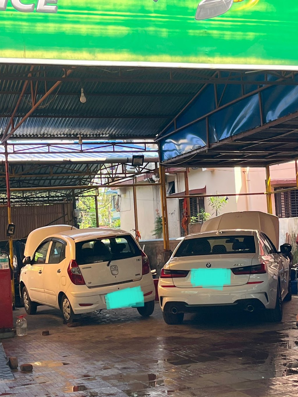 Two white cars with open hoods parked side-by-side under the metal-roofed service bay at S.S Automobile.
