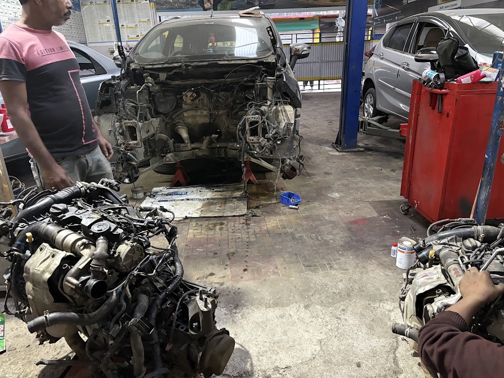 Car engine overhaul in progress at S.S Automobile with a disassembled vehicle chassis and technician working on a removed engine block.